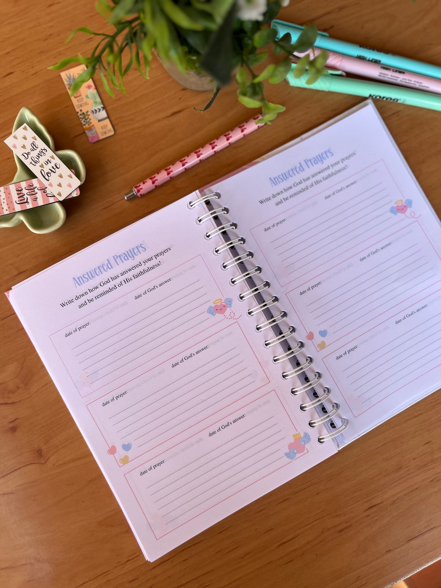 Open prayer journal on a wooden table with stationery items