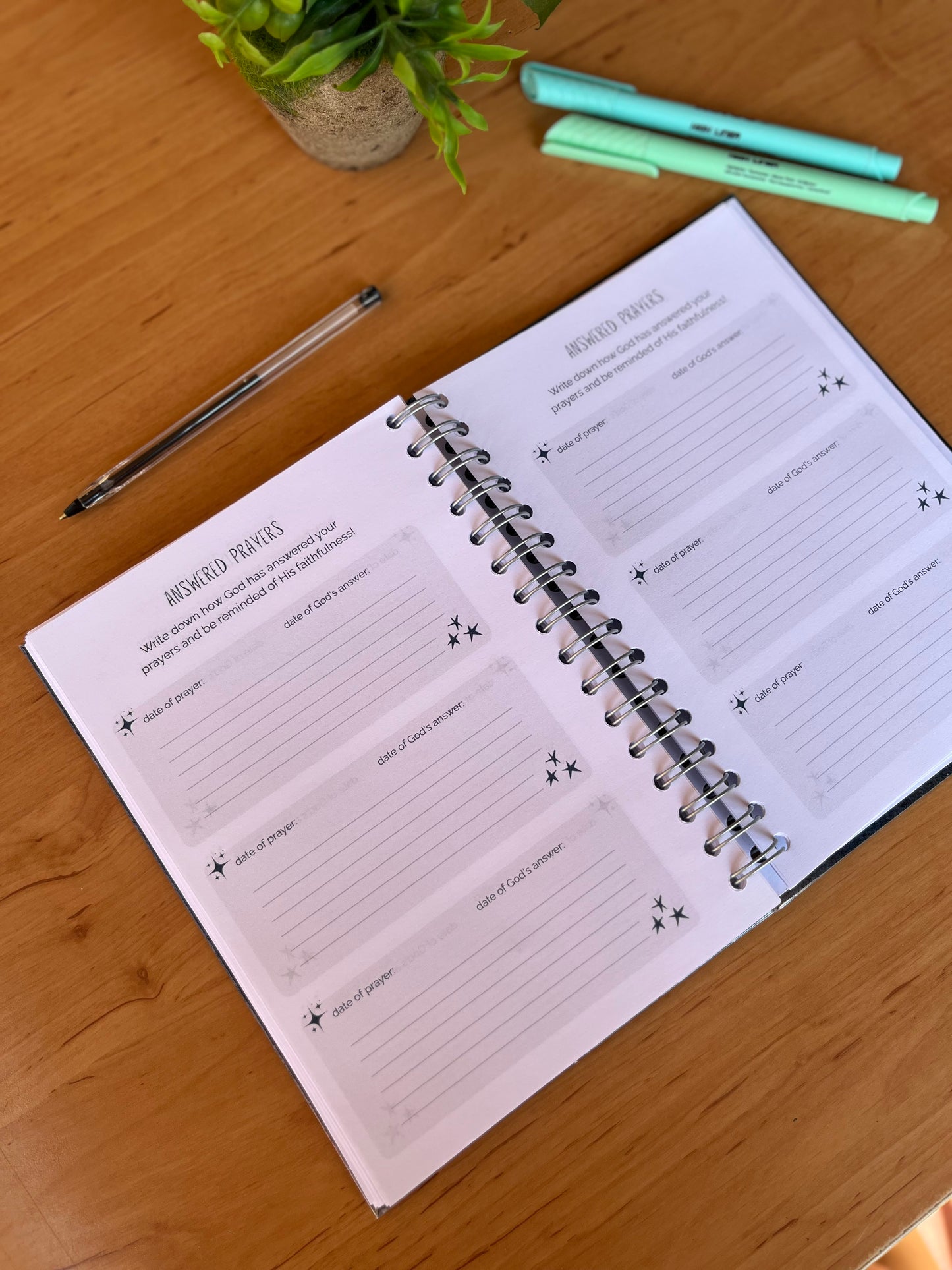 Open prayer journal on a wooden surface with highlighters and a pen