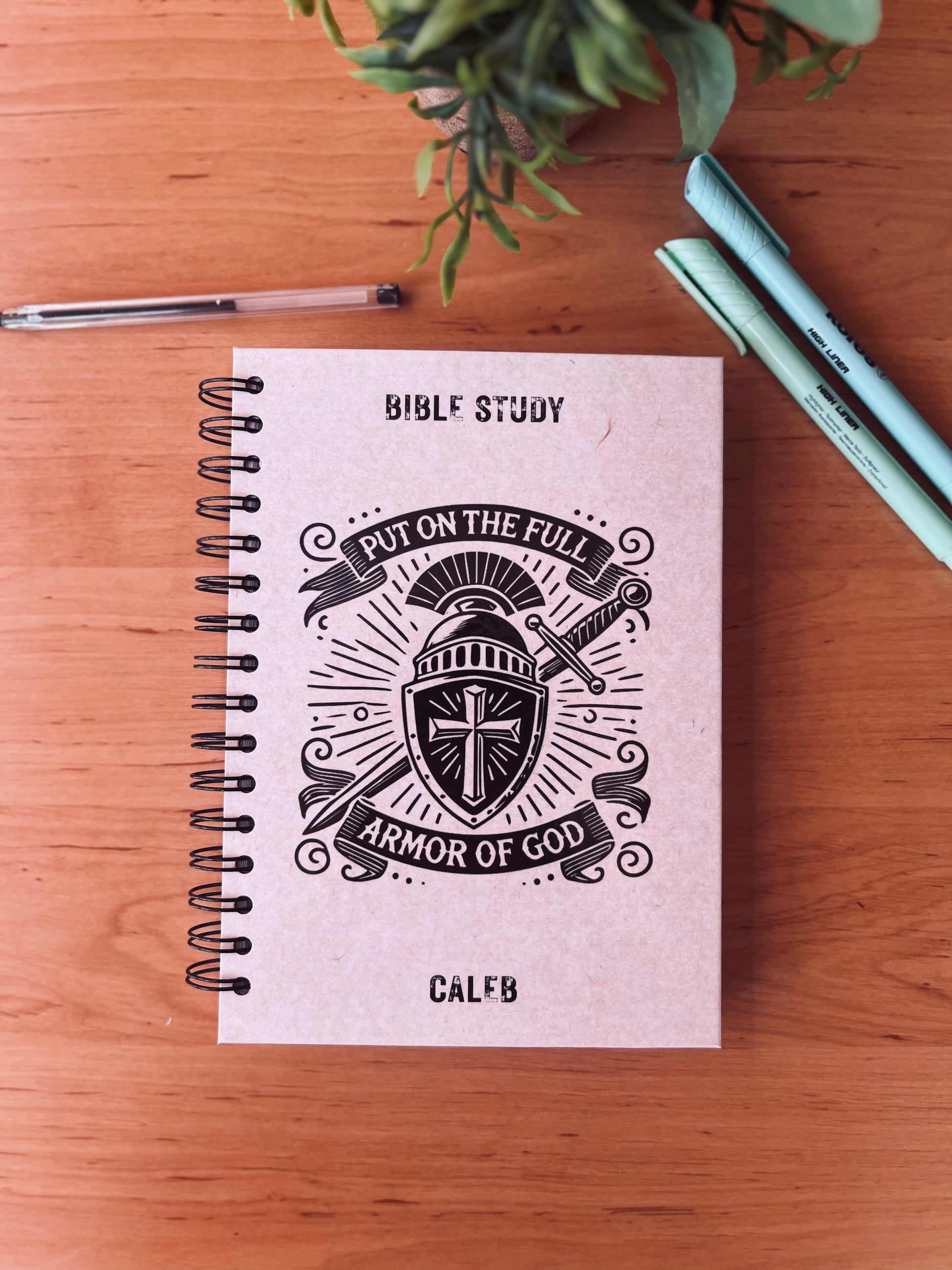 Notebook titled 'Bible Study' with 'Put on the Full Armor of God' design on a wooden surface.