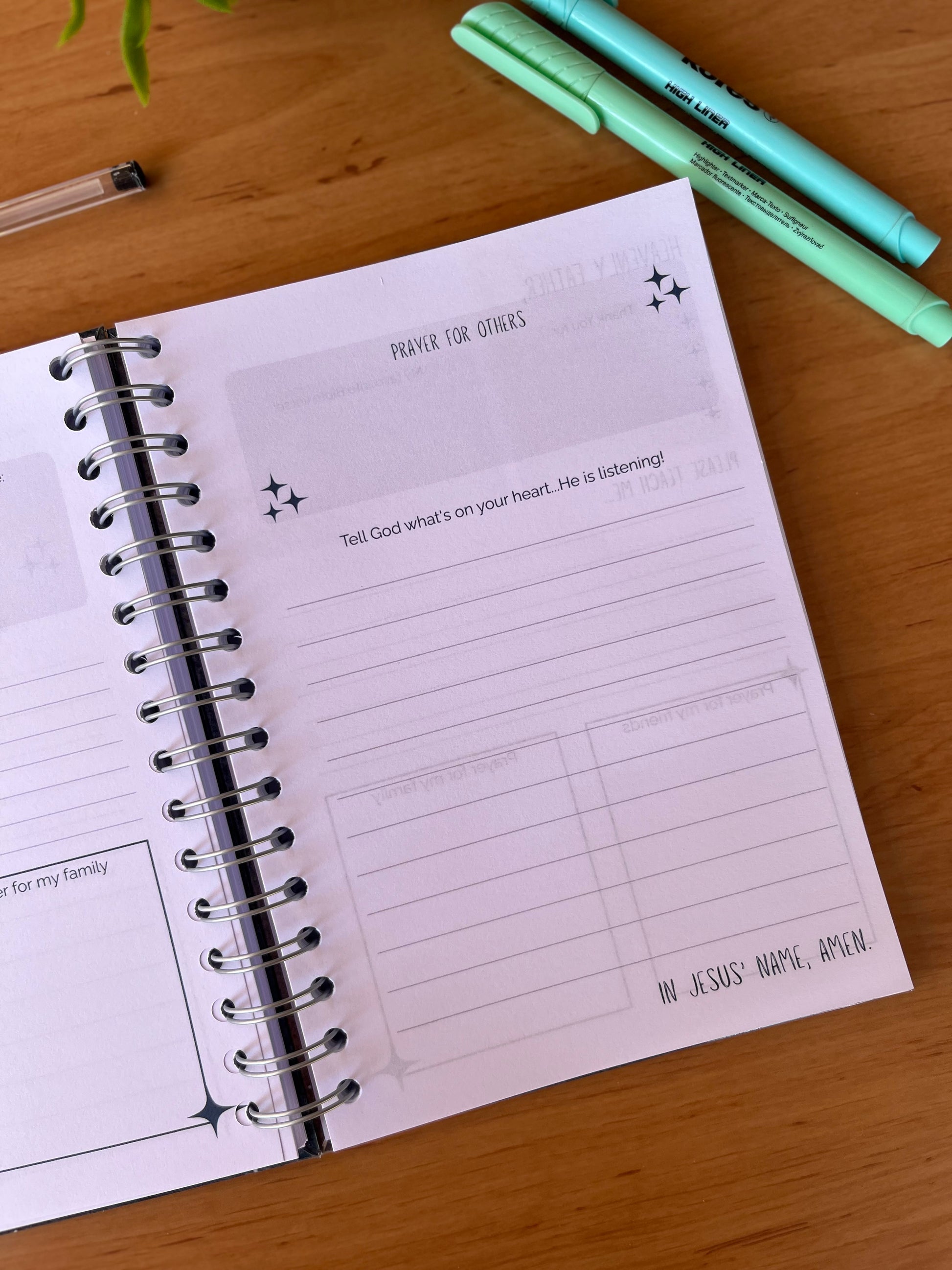 Open prayer journal pages on a wooden surface with markers.