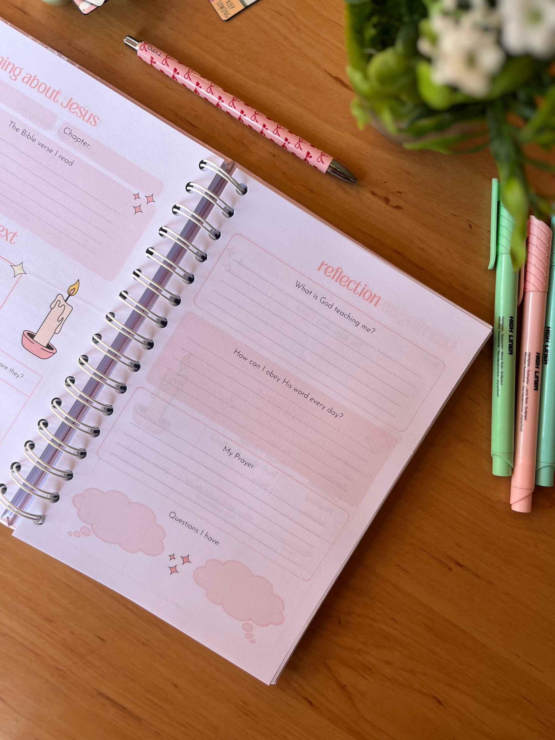 Open journal with reflection section on a wooden surface with pens and flowers