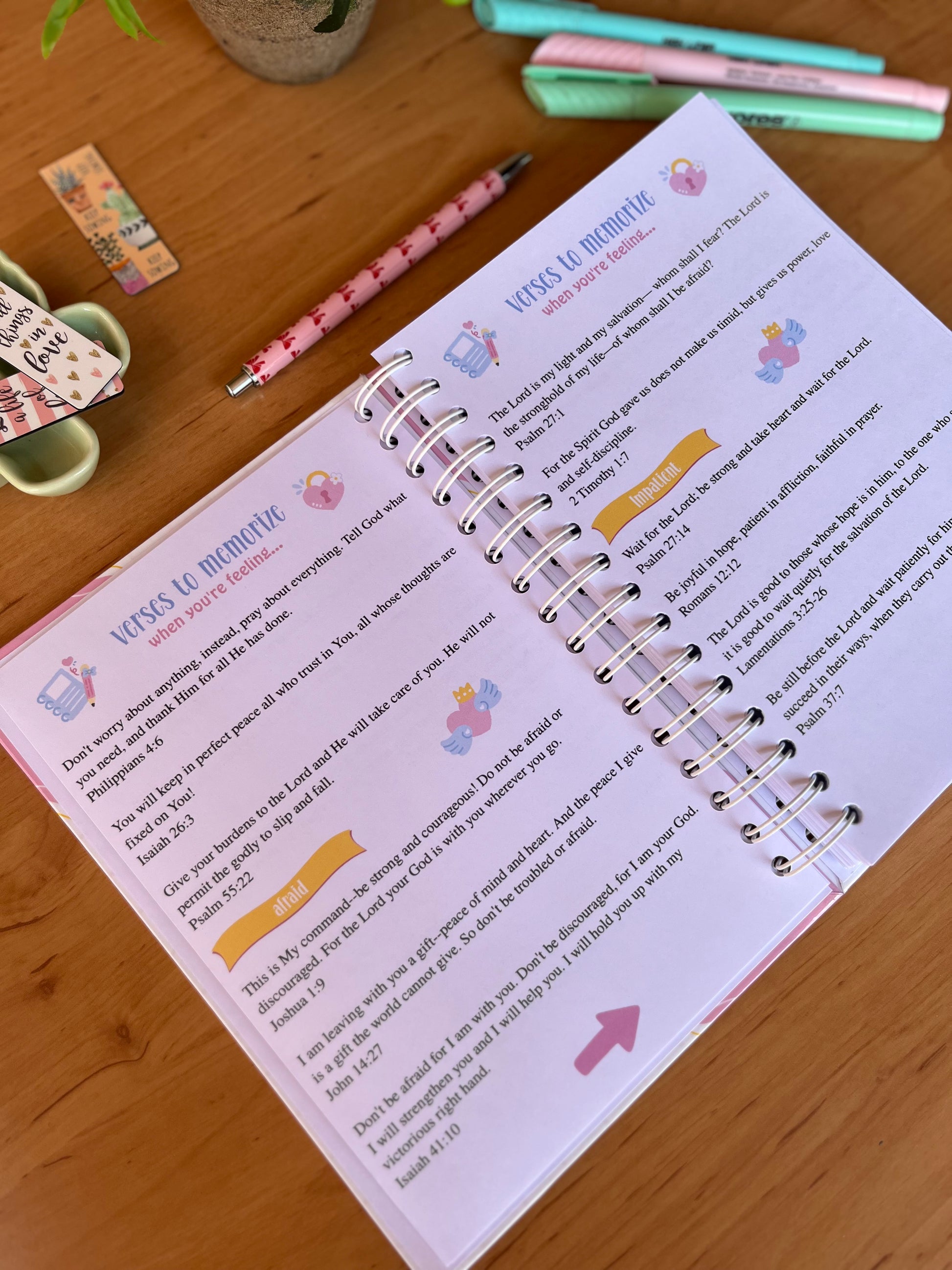 Open spiral-bound journal on a wooden surface with stationery items around